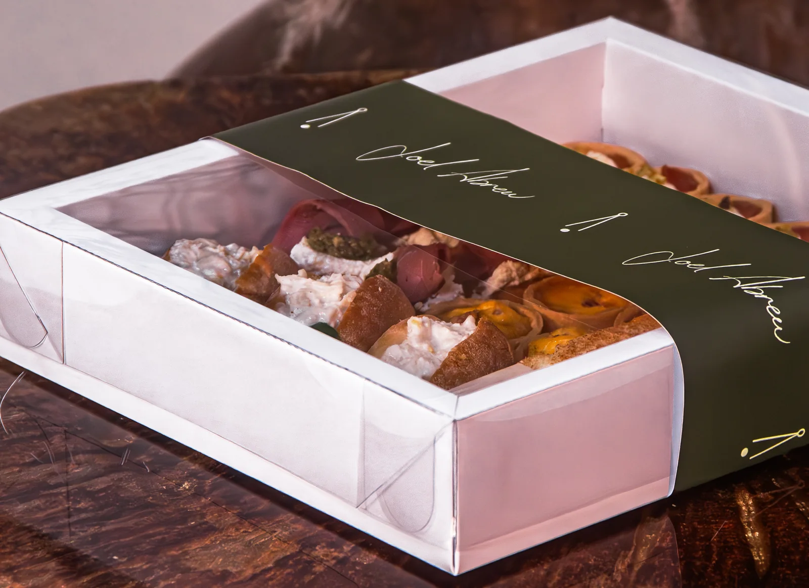 Box de canapés do ateliê Joel Abreu, com cinta assinada pelo chef